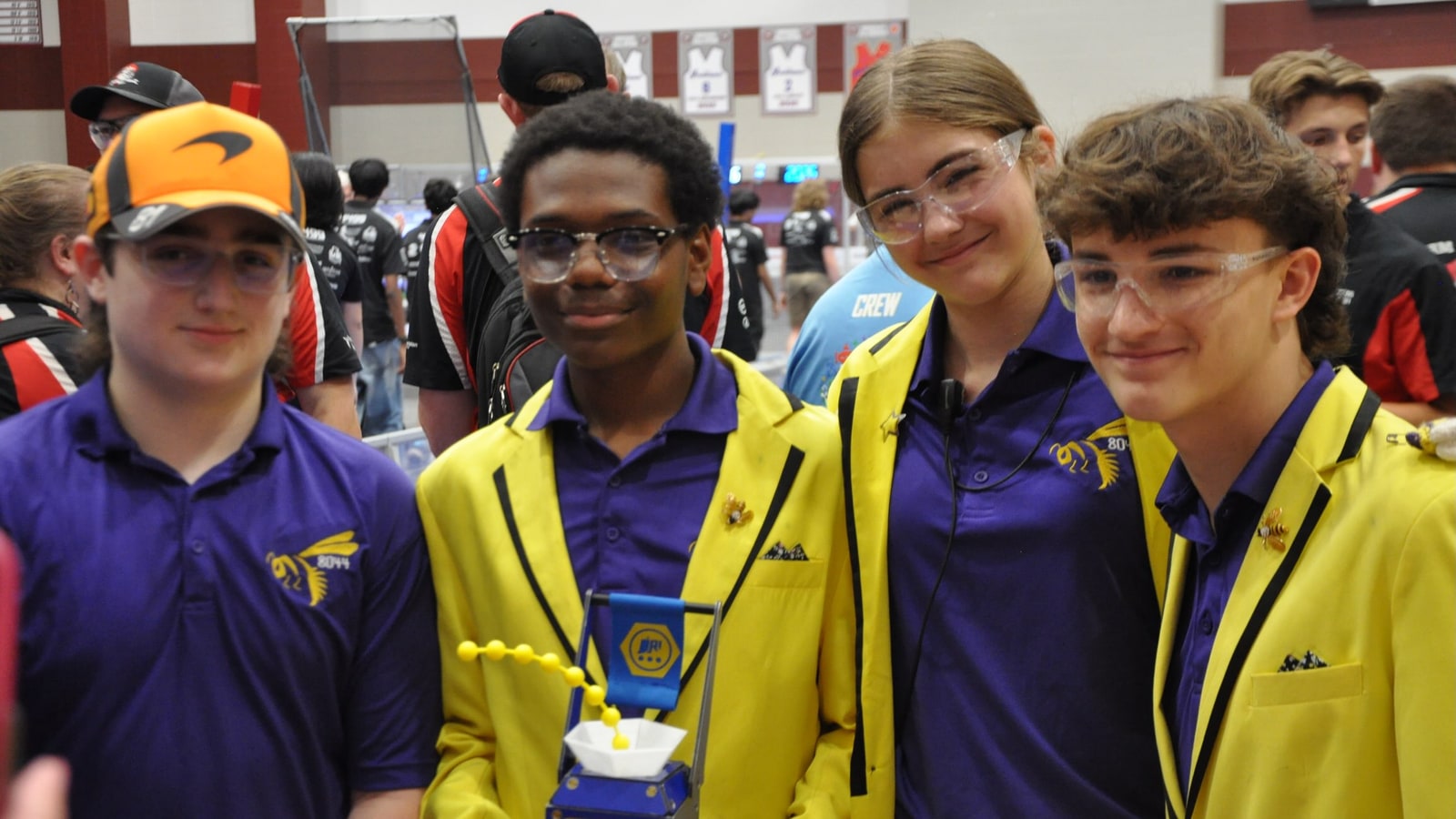 Four Team 8044 students in purple shirts and yellow jackets posing with a trophy at the Indiana Robotics Invitational.